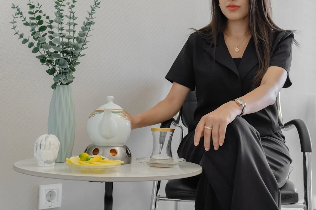 Une femme en pull gris nettoie une table avec soin, illustrant le ménage à domicile dans un cadre confortable.